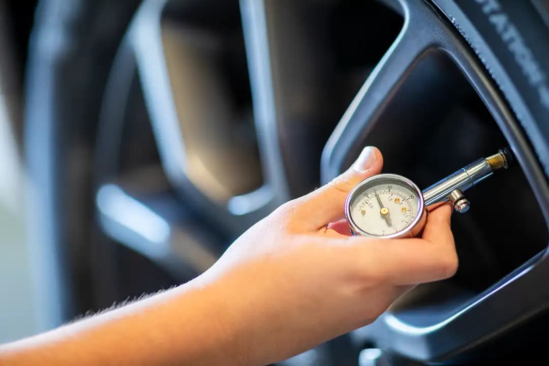 ميكانيكي يفحص ضغط الإطارات للتأكد من الضغط المثالي